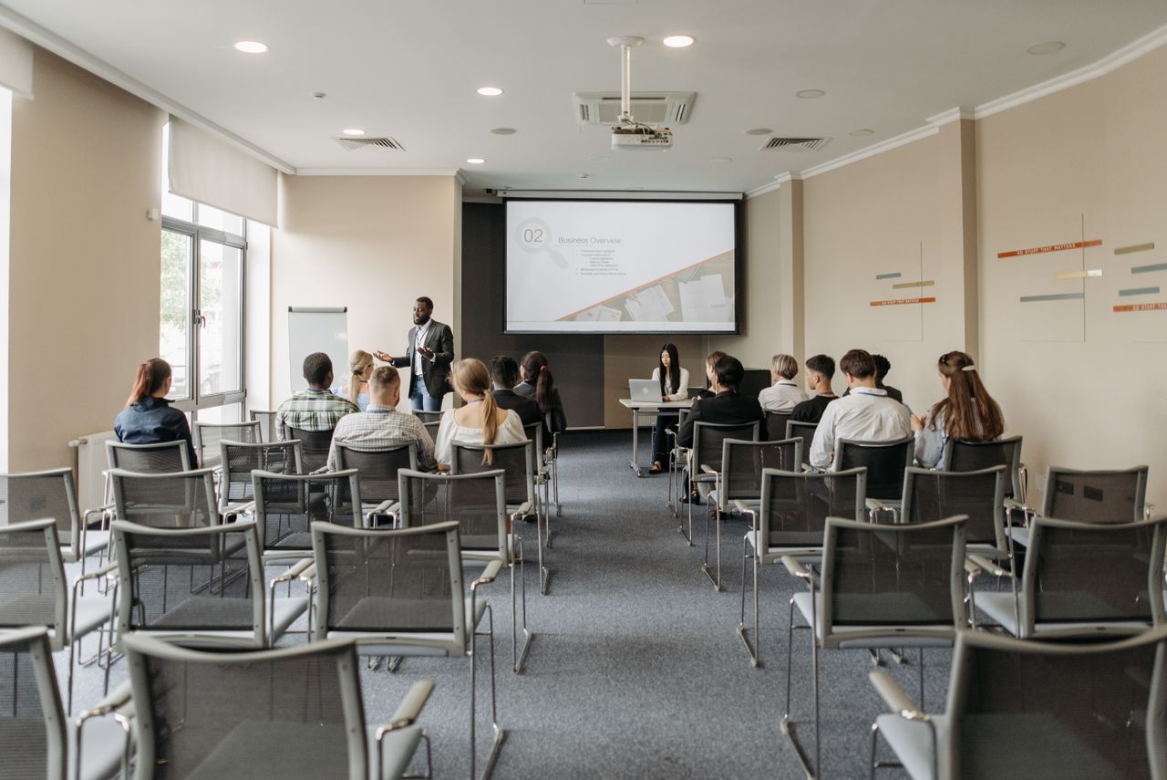 services-01 A group attending a business presentation in a modern conference room with projector.